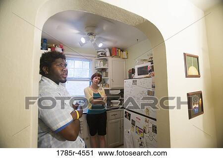 Contemplative inter-racial couple standing in a kitchen View Large Photo Image Stock Image - Contemplative inter-racial couple standing in a kitchen. Fotosearch
