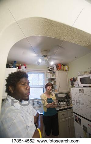 Contemplative inter-racial couple standing in a kitchen View Large Photo Image Stock Image - Contemplative inter-racial couple standing in a kitchen. Fotosearch