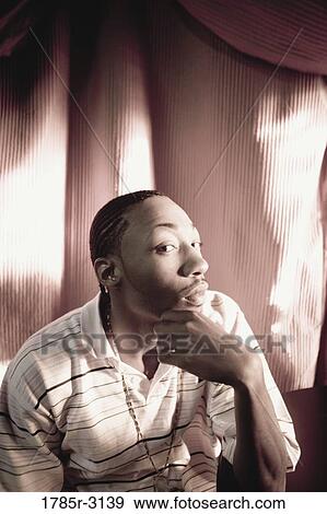 Contemplative young man in hip-hop fashion sitting at a table View Large Photo Image Stock Photo - Contemplative young man in hip-hop fashion sitting at a table. Fotosearch