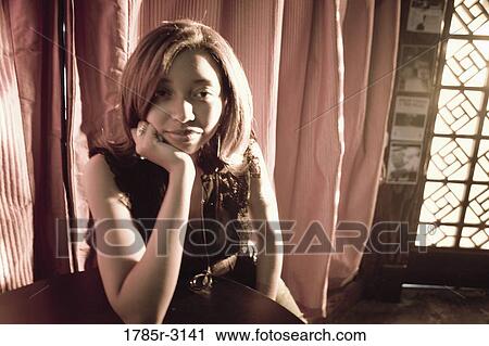 Contemplative young woman in hip-hop fashion sitting at a table View Large Photo Image Stock Image - Contemplative young woman in hip-hop fashion sitting at a table. Fotosearch