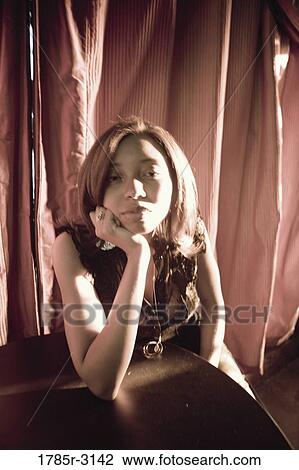 Contemplative young woman in hip-hop fashion sitting at a table View Large Photo Image Stock Image - Contemplative young woman in hip-hop fashion sitting at a table. Fotosearch