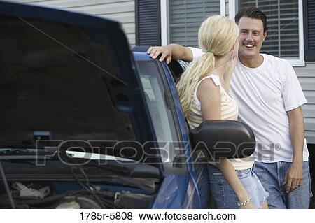 Couple conversing while leaning against old truck outside house View Large Photo Image Stock Photo - Couple conversing while leaning against old truck outside house. Fotosearch