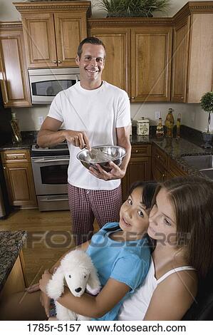 Stock Photo - Dad preparing breakfast for his two daughters. Fotosearch