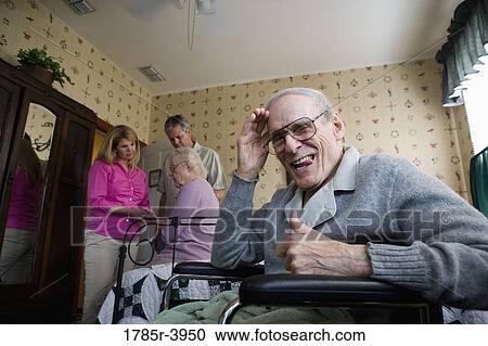 Stock Image - Elderly man saluting camera with spouse and adult children in background. Fotosearch