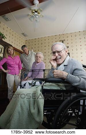 Elderly man whispering to camera with spouse and adult children in background View Large Photo Image Stock Image - Elderly man whispering to camera with spouse and adult children in background. Fotosearch