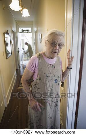 Elderly woman standing in hallway with feeble senior man in the background View Large Photo Image Stock Photo - Elderly woman standing in hallway with feeble senior man in the background. Fotosearch