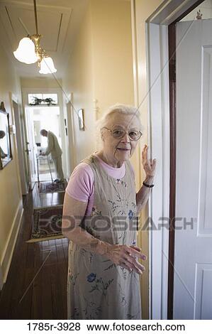 Elderly woman standing in hallway with feeble senior man in the background View Large Photo Image Stock Photo - Elderly woman standing in hallway with feeble senior man in the background. Fotosearch