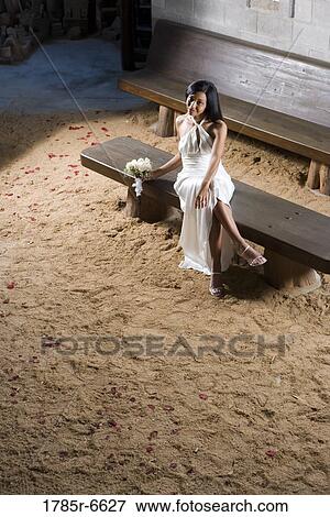 Stock Photo - Elevated view of a young bride in a white gown sitting on a bench inside a medieval castle. Fotosearch