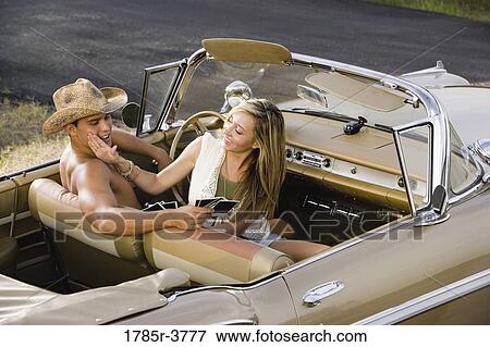 Stock Photo - Elevated view of a young couple sitting in antique convertible car. Fotosearch