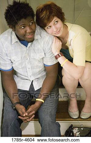 Picture - Elevated view of a young inter-racial couple sitting on stairs. Fotosearch