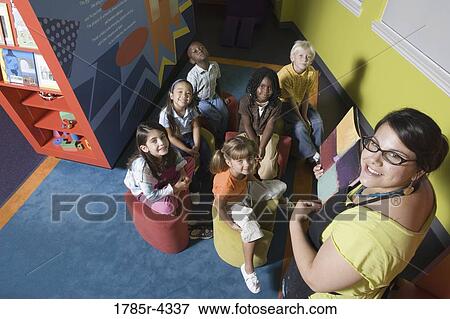 Elevated view of an teacher reading to young boys and girls View Large Photo Image Stock Photo - Elevated view of an teacher reading to young boys and girls. Fotosearch