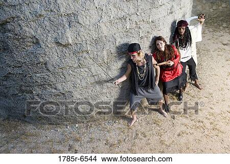 Picture - Elevated view of armed pirates sneaking around a castle wall. Fotosearch