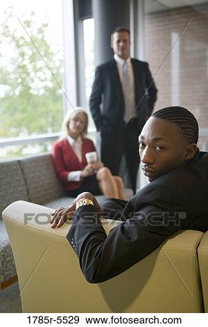 Stock Photo - Elevated view of business people sitting and waiting in an office lounge area. Fotosearch