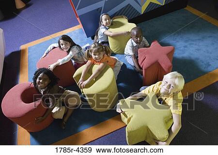 Elevated view of children hugging colorful seats of various shapes View Large Photo Image Stock Photo - Elevated view of children hugging colorful seats of various shapes. Fotosearch