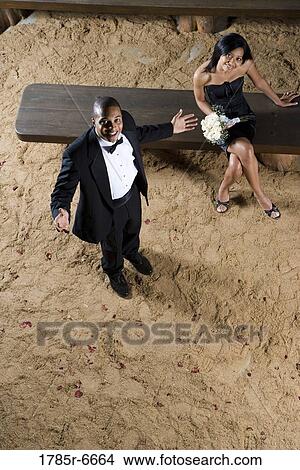 Elevated view of couple in formal attire inside on a wooden bench View Large Photo Image Picture - Elevated view of couple in formal attire inside on a wooden bench. Fotosearch