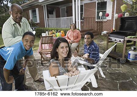 Family and friends enjoying backyard barbeque View Large Photo Image Stock Image - Family and friends enjoying backyard barbeque. Fotosearch