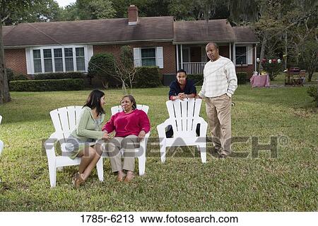 Stock Image - Family and friends relaxing in backyard. Fotosearch