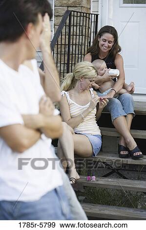 Family and friends relaxing on front steps of a home View Large Photo Image Stock Photo - Family and friends relaxing on front steps of a home. Fotosearch