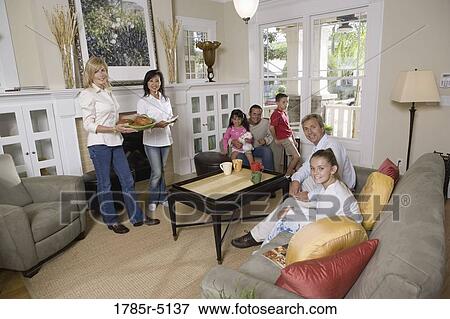 Stock Photo - Family and friends together in living room. Fotosearch