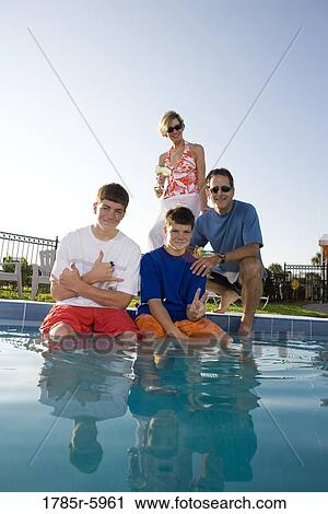 Stock Image - Family at the edge of a swimming pool. Fotosearch
