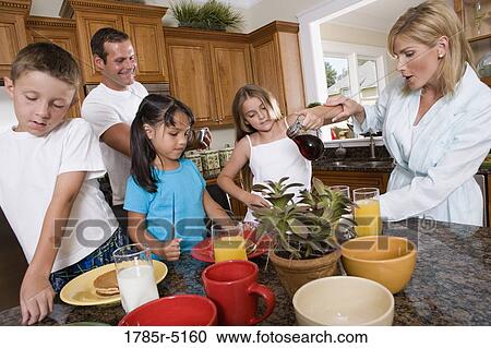 Stock Image - Family having breakfast in the kitchen. Fotosearch
