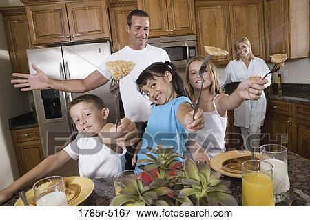 Stock Photo - Family having breakfast in the kitchen. Fotosearch
