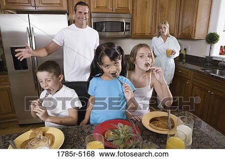 Stock Photo - Family having breakfast in the kitchen. Fotosearch