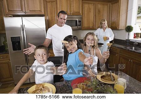 Stock Photograph - Family having breakfast in the kitchen. Fotosearch