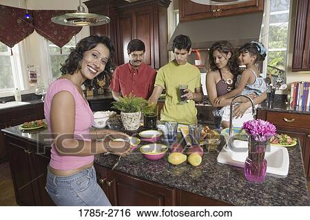 Stock Photograph - Family in the kitchen with mother preparing food. Fotosearch