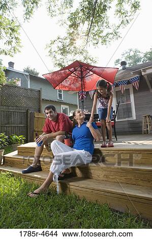 Family on backyard patio with 4th of July decorations in background View Large Photo Image Picture - Family on backyard patio with 4th of July decorations in background. Fotosearch