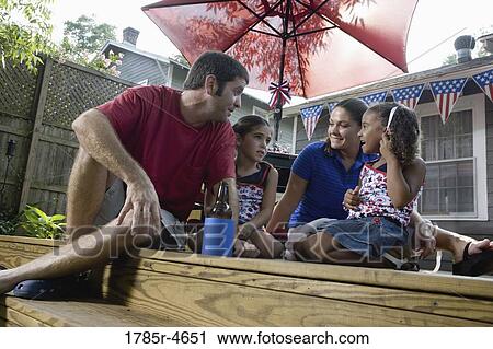 Stock Image - Family on backyard patio with 4th of July decorations in background. Fotosearch