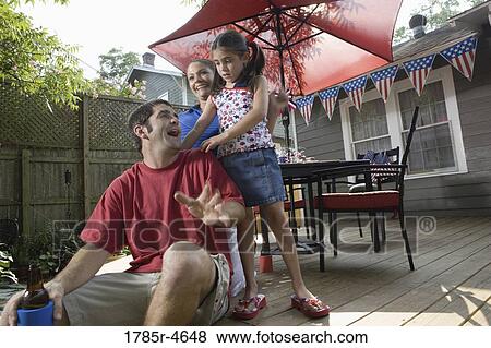 Family on backyard patio with 4th of July decorations in background View Large Photo Image Stock Photo - Family on backyard patio with 4th of July decorations in background. Fotosearch