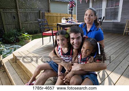 Family on backyard patio with 4th of July decorations in background View Large Photo Image Stock Photo - Family on backyard patio with 4th of July decorations in background. Fotosearch