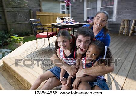 Stock Photograph - Family on backyard patio with 4th of July decorations in background. Fotosearch