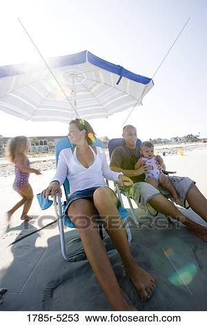 Family on beach sitting under umbrella View Large Photo Image Stock Image - Family on beach sitting under umbrella. Fotosearch