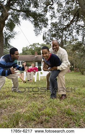 Stock Photo - Family playing football in backyard. Fotosearch