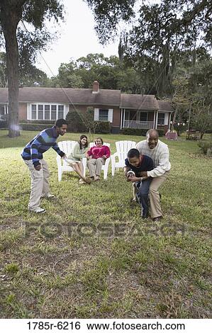 Stock Photograph - Family playing football in backyard. Fotosearch