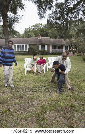 Stock Photography - Family playing football in backyard. Fotosearch