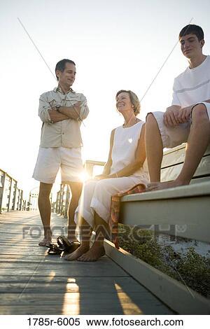 Family sitting on wooden pier at beach at sunrise View Large Photo Image Stock Photography - Family sitting on wooden pier at beach at sunrise. Fotosearch