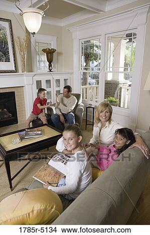Family sitting together in the living room View Large Photo Image Picture - Family sitting together in the living room. Fotosearch