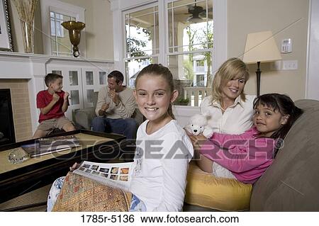 Family sitting together in the living room View Large Photo Image Stock Photograph - Family sitting together in the living room. Fotosearch
