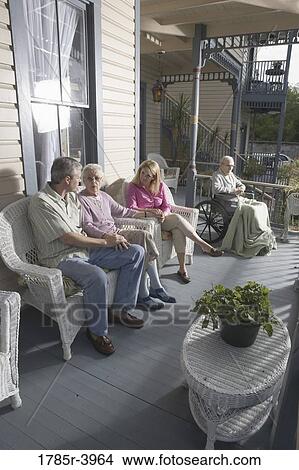 Family with elderly parents and adult children sitting together on front porch View Large Photo Image Picture - Family with elderly parents and adult children sitting together on front porch. Fotosearch