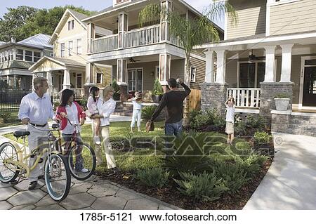 Stock Image - Family with young children conversing with neighbors in front of house. Fotosearch