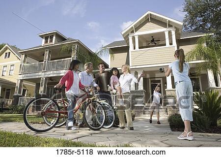 Stock Photo - Family with young children conversing with neighbors in front of house. Fotosearch