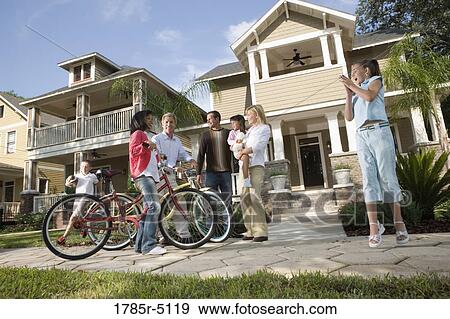 Stock Photo - Family with young children conversing with neighbors in front of house. Fotosearch