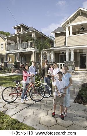 Stock Image - Family with young children standing with neighbors in front of house. Fotosearch