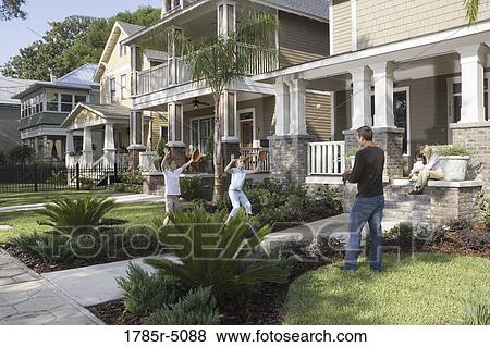 Stock Photo - Father and children playing catch in front yard. Fotosearch