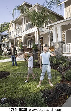 Stock Photography - Father and children playing catch in front yard. Fotosearch