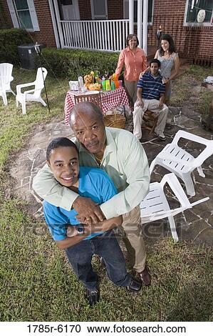 Father and son enjoying backyard bbq with family in background View Large Photo Image Stock Image - Father and son enjoying backyard bbq with family in background. Fotosearch
