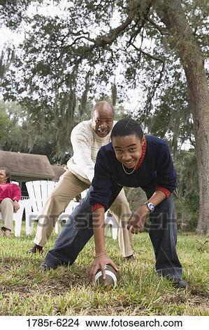 Picture - Father and son playing football in backyard. Fotosearch